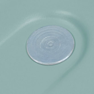 A close-up image of a smooth, round, metallic pin on a pale green surface.