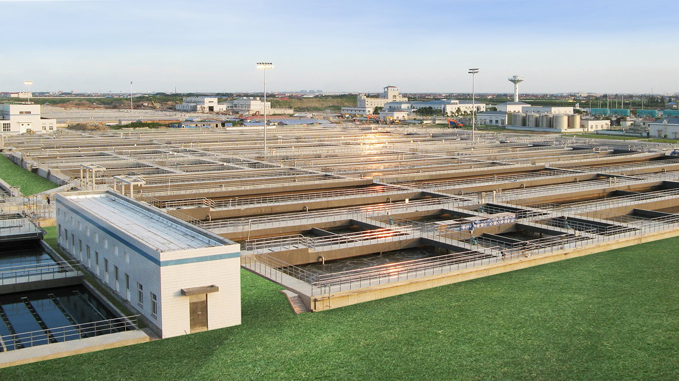 A sprawling wastewater treatment plant featuring Polychem® Systems with multiple rectangular treatment pools is shown. The facility includes several buildings and a network of catwalks and piping